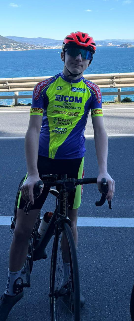 Edoardo in sella alla sua bici con la maglia del Pedale Castellano, sulla strada lungo il mare